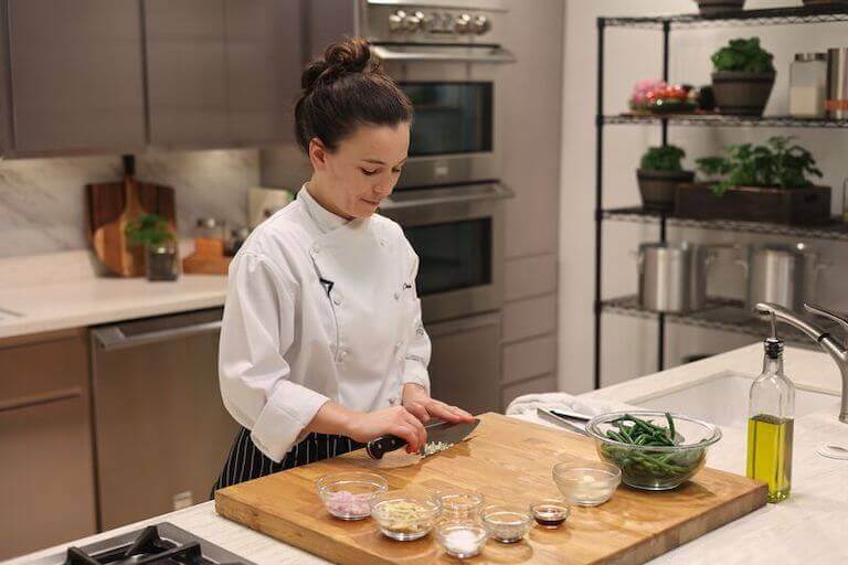 Chef chopping garlic on a large wooden cutting board