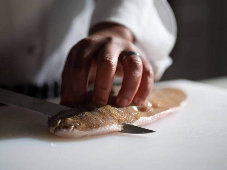 Chef cutting a round fish fillet