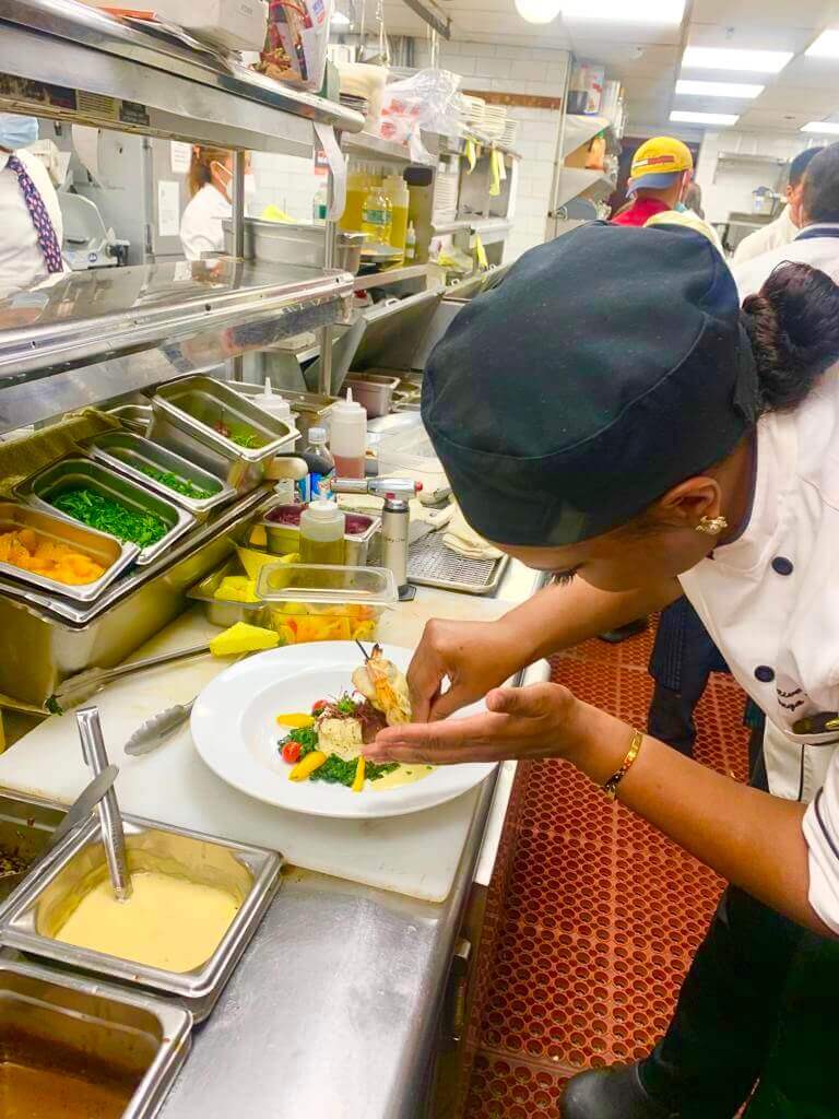 Escoffier student plating a dish in a restaurant kitchen 