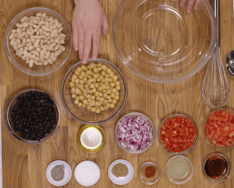 Three bean salad ingredients separated into glass bowls