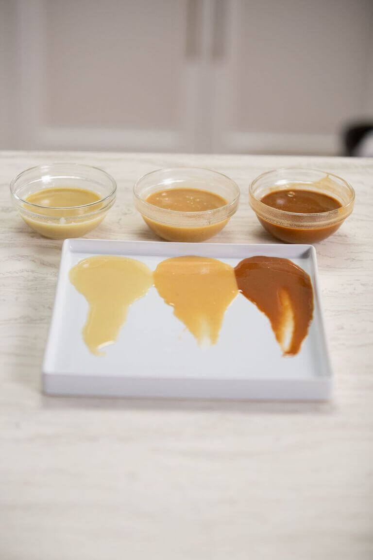 Three different roux varieties displayed in glass bowls with a white tray in front that has the roux's spread out