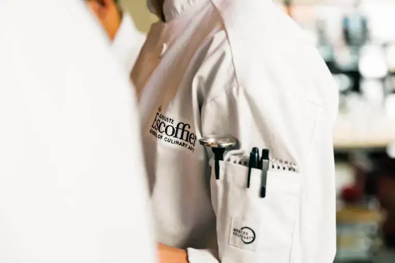 Close-up of an Escoffier student’s chef uniform with sleeve pocket holding pens