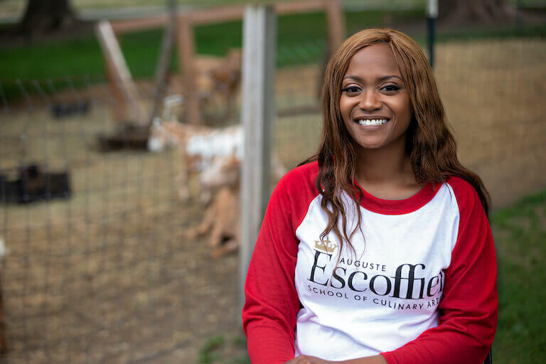 Escoffier student wearing a red and white shirt smiling outside