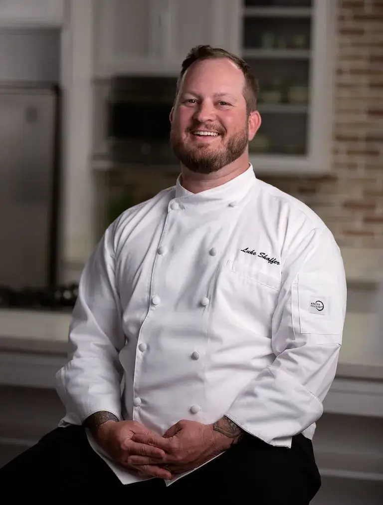 Portrait of a smiling Chef Instructor in chef whites in a teaching kitchen.