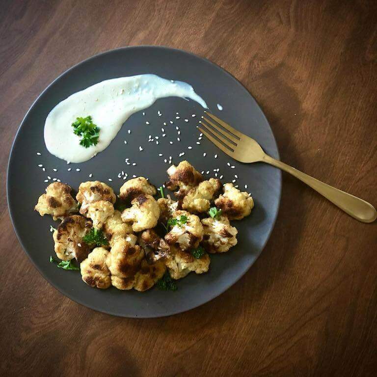 Roasted cauliflower with tahini sauce on a grey plate