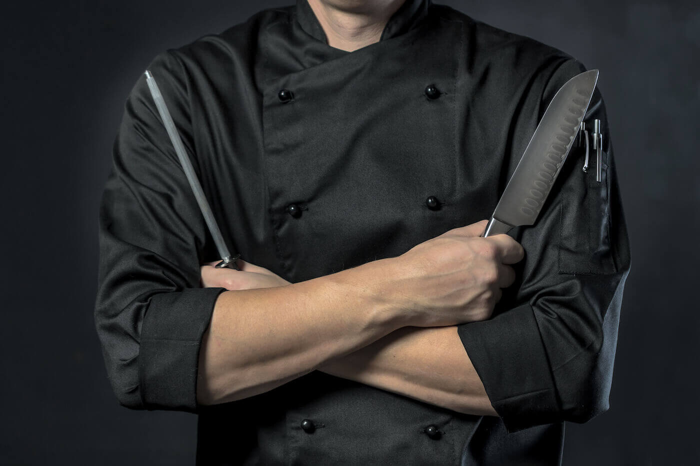 https://www.escoffier.edu/wp-content/uploads/2022/08/Chef-in-uniform-holding-two-knives-with-their-arms-crossed-1400.jpeg