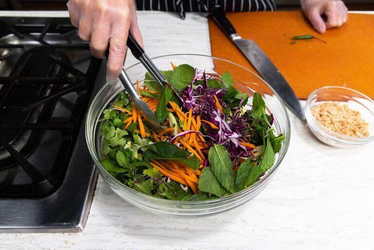 Chef mixing an Asian inspired Cabbage Salad