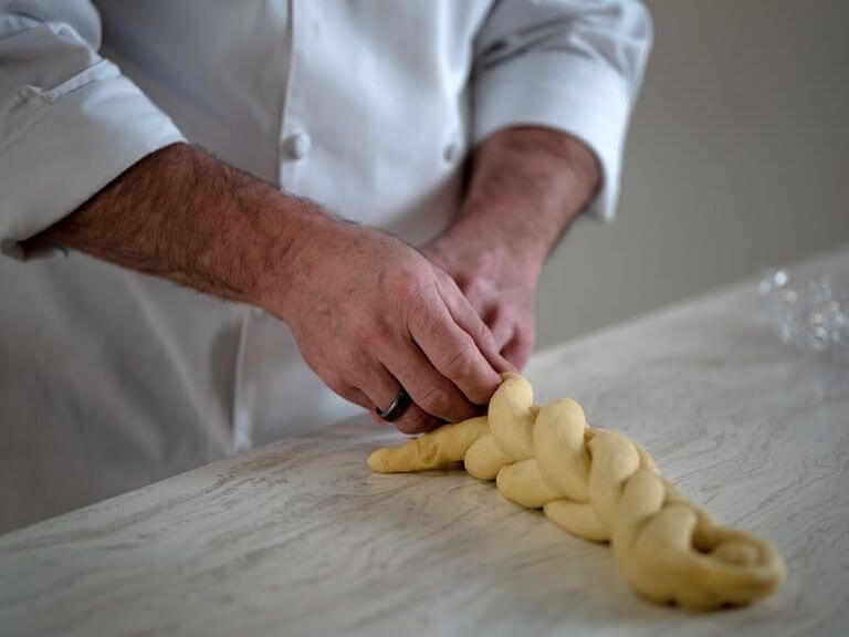 Close up of chef hands braiding challah bread dough