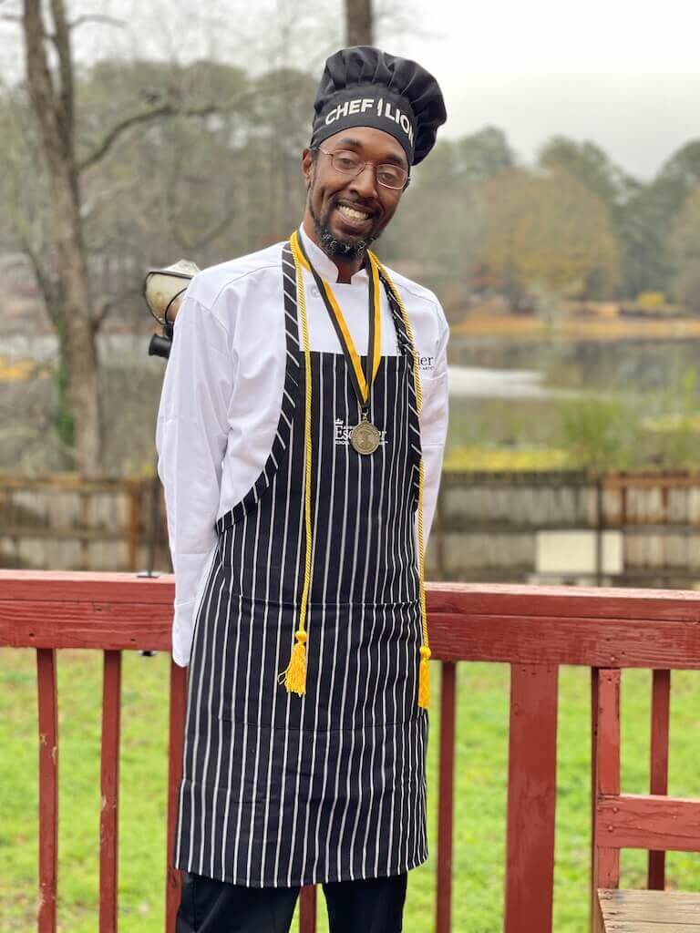 Escoffier graduate posing in uniform with a medal around their neck