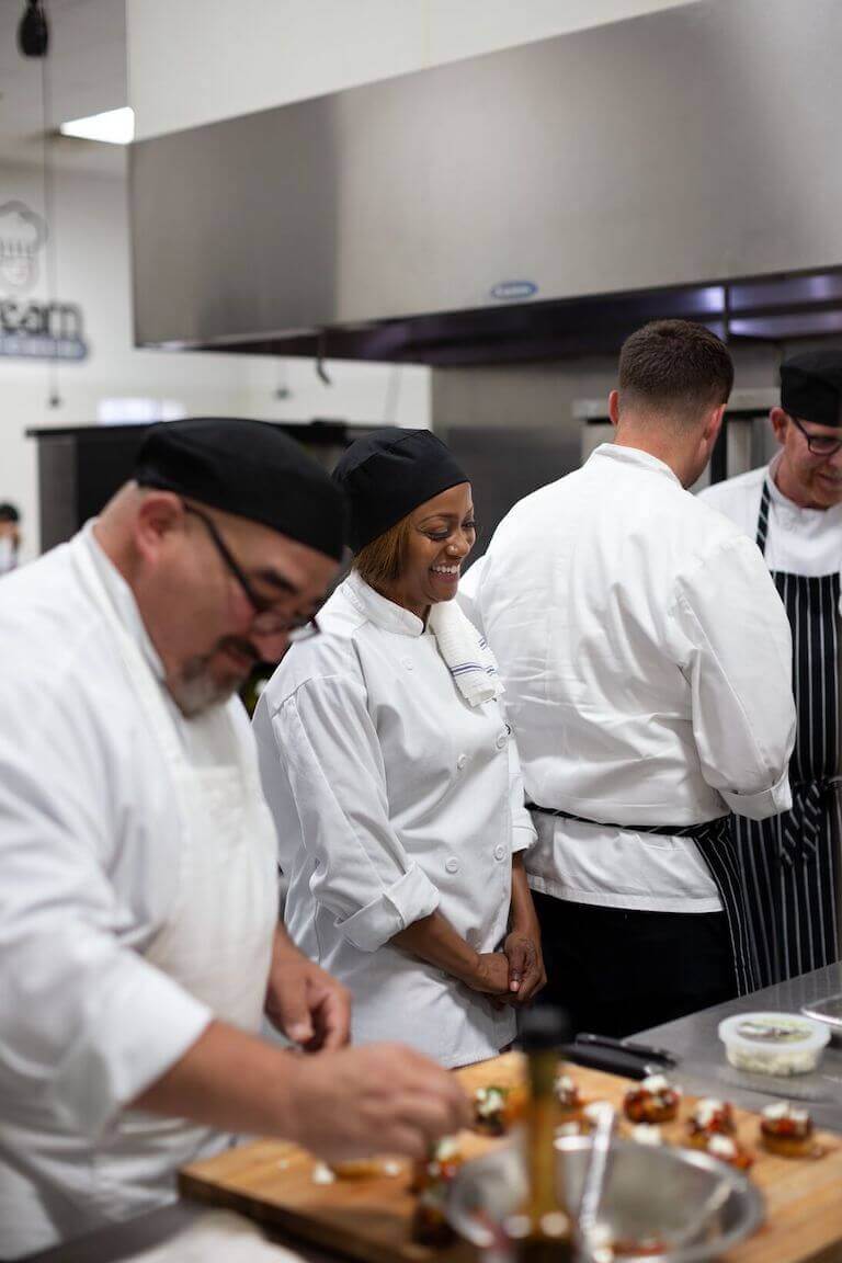 Escoffier students in a commercial kitchen making bruschetta