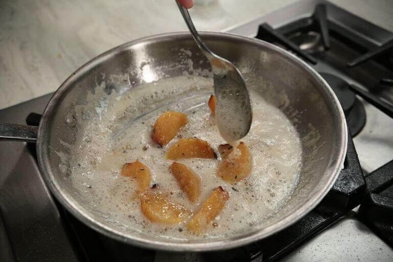 Whole roasted Celeriac being stirred in a silver pan