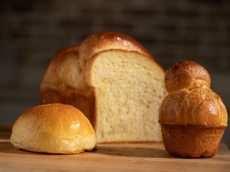 Brioche bun and loaf of bread on a cutting board