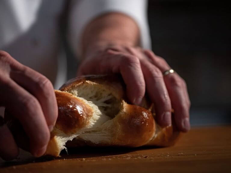 Chef pulling apart fresh challah bread