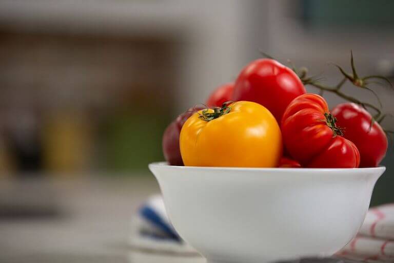 Ripe red and orange tomatoes in a white bowl 