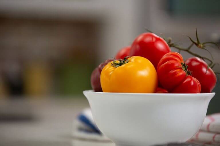 Ripe red and orange tomatoes in a white bowl