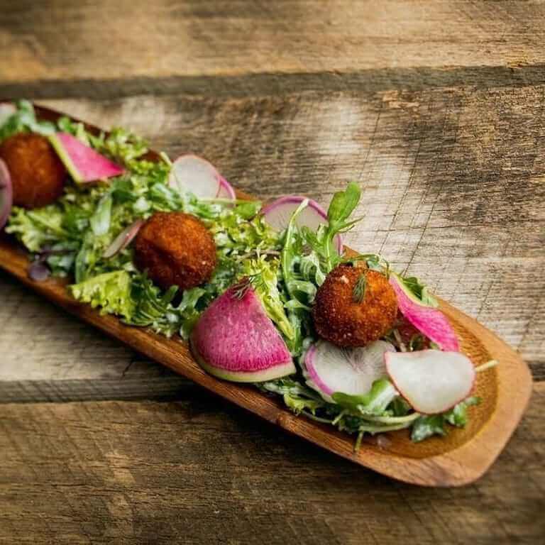 Salad topped with fried croutons on a wooden tray