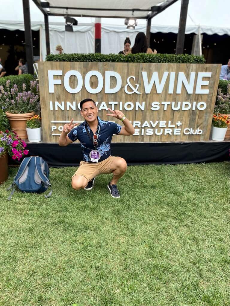 Student posing for a photo in front of a food and wine sign