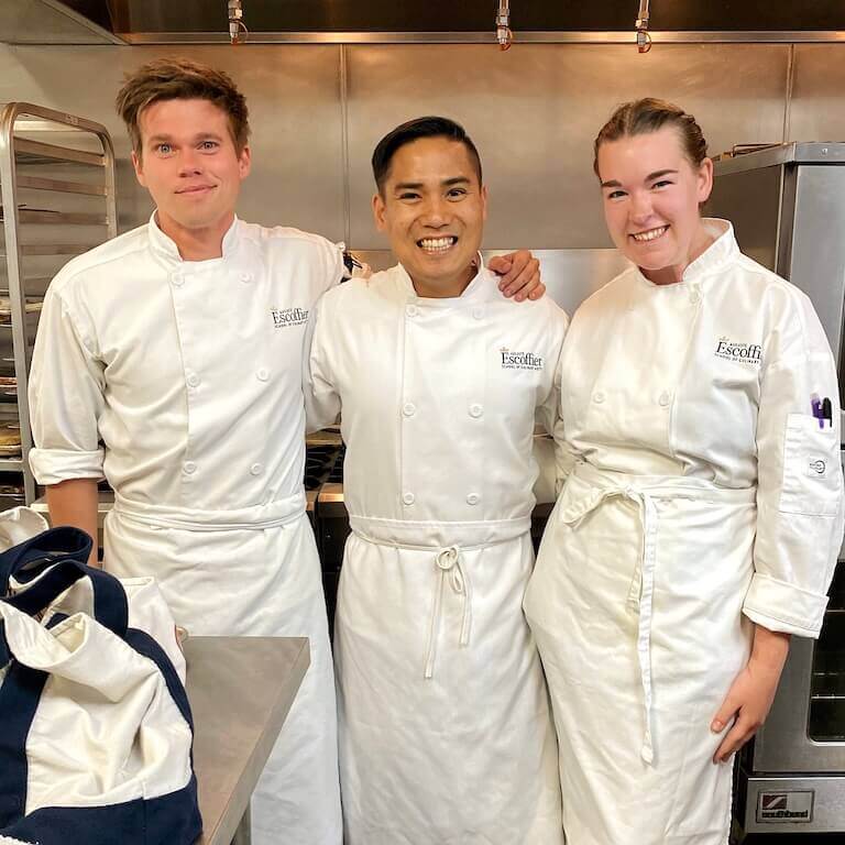 Three escoffier students posing for a photo in a kitchen