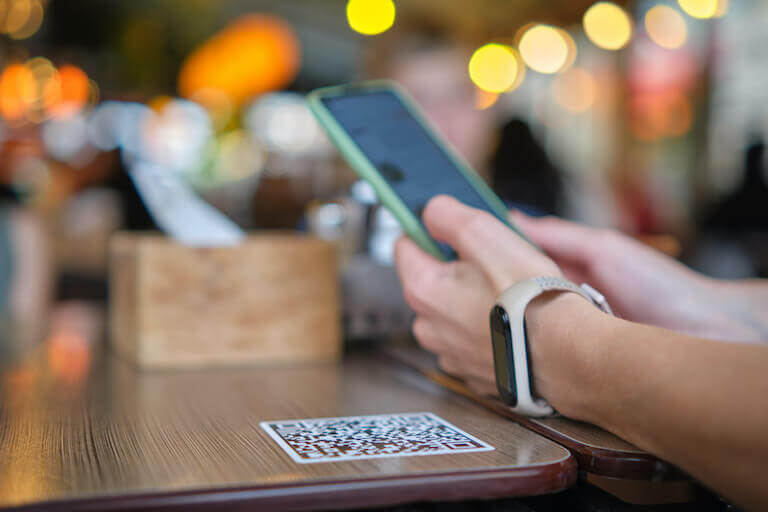 Close up of hands using a mobile device to scan a QR code and order a meal