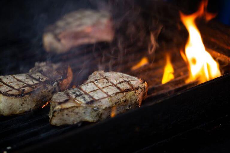 Pork chops with grill marks on a grill with a flame