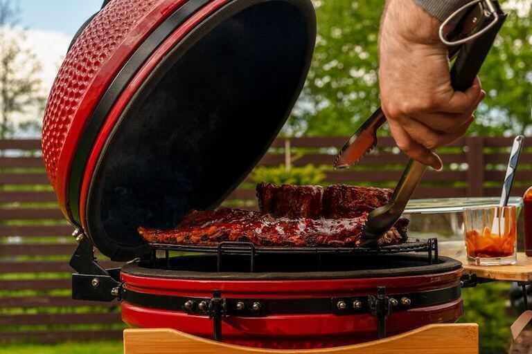 Ribs being grilled on a red ceramic grill
