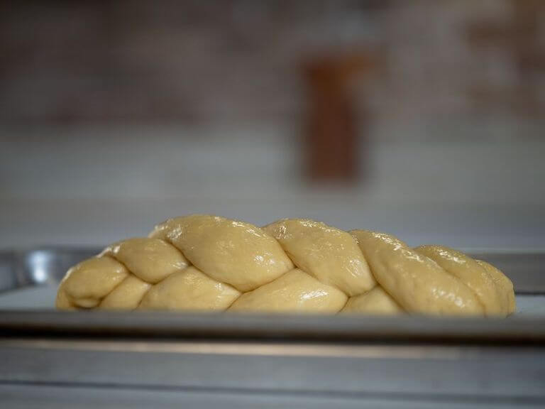 Egg washed challah bread on a cooking sheet