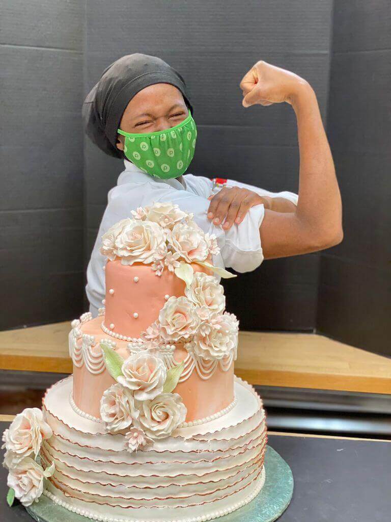 Merisauh Gamble flexing behind her finished cake
