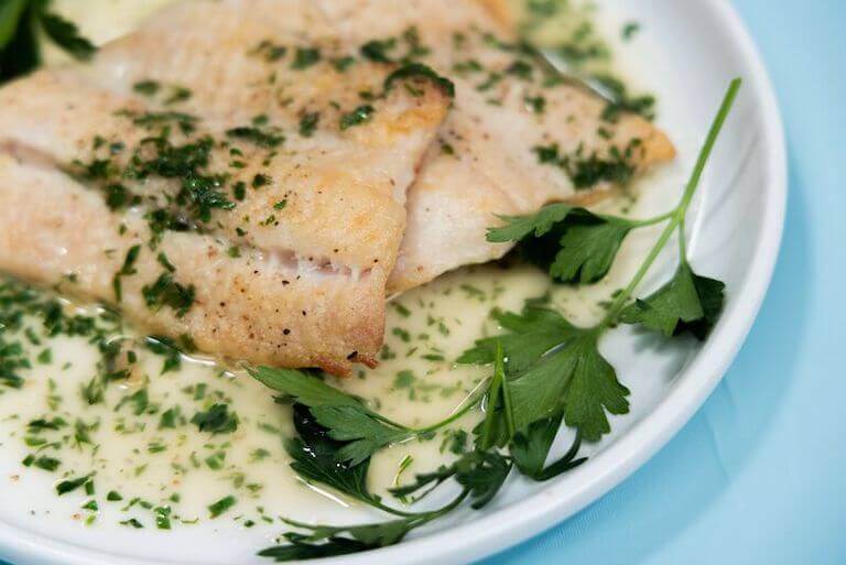 Pan seared white fish on a white plate