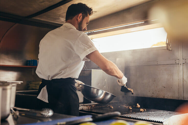 Chef cooking on a large grill in a food truck