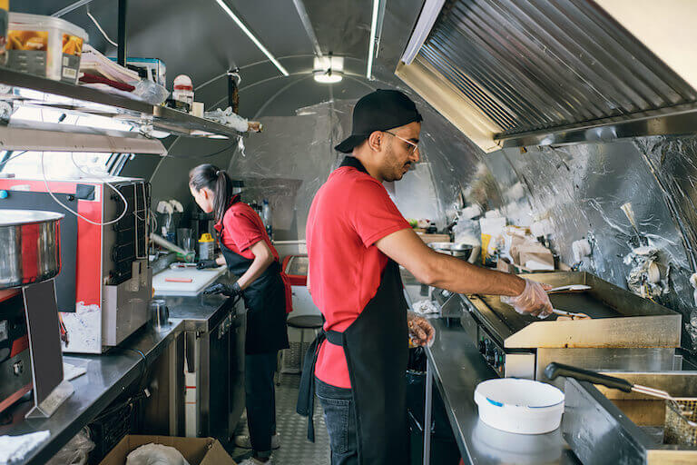 Cook wearing gloves putting food on an electric stove in a food truck