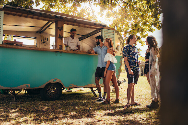 Couple wearing shorts ordering food from a blue food truck