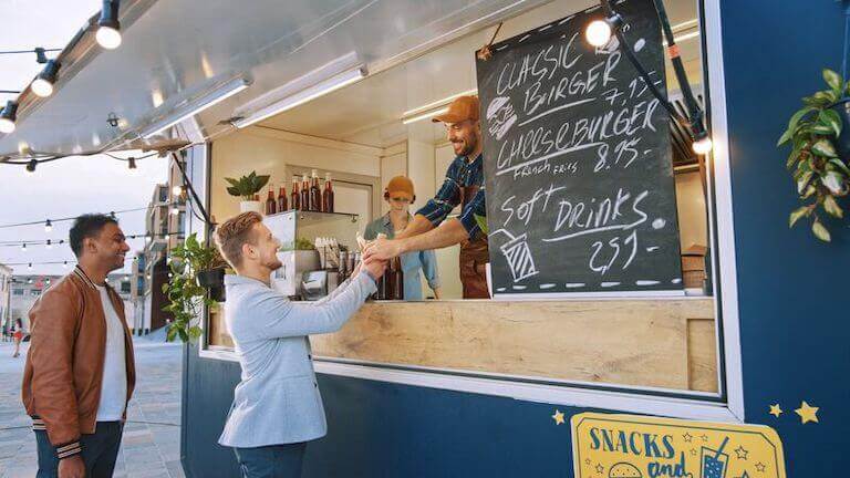 Food Truck Employee hands out a burger to a happy customer in a suit