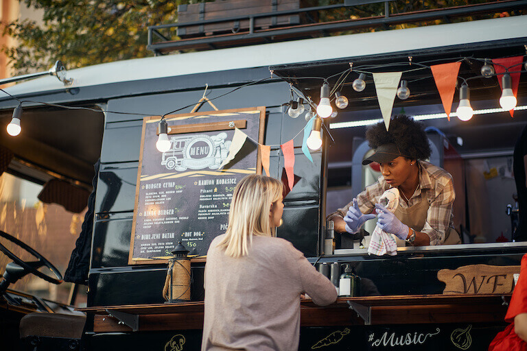 Food truck employee leaning out the window speaking to a customer