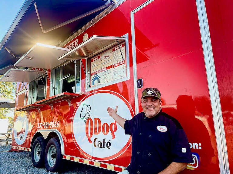 Food truck owner standing in front of red truck named Qdog