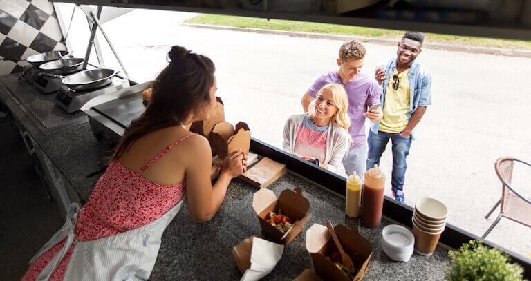 Smiling customers ordering food at a food truck window