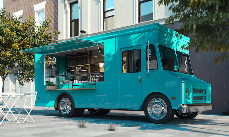 Teal food truck parked in front of a building