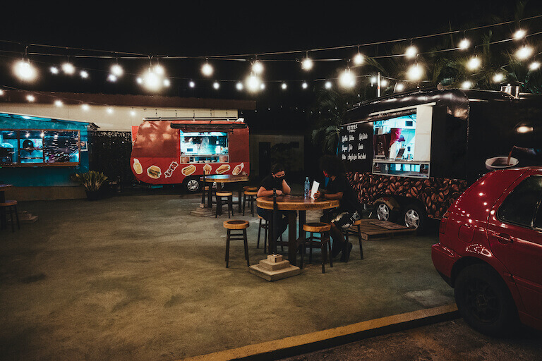 Three food trucks lined up with tables in the middle