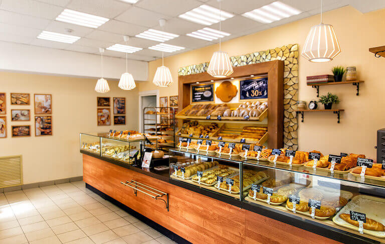 Baked baguettes and pies on showcase in bakery shop