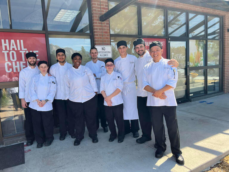 Oscar Beltran posing for a photo with a group of escoffier students