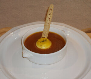 Roasted Vegetable Soup with Goat Cheese Custard in white bowl on white plate