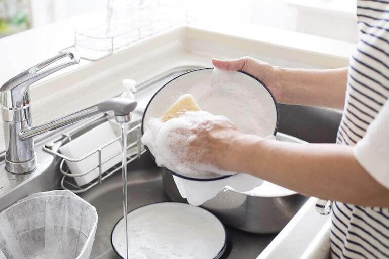 Soapy hand washing dishes in a sink