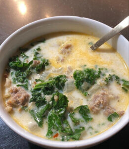 Tuscan Soup in white bowl with spinach and sausage
