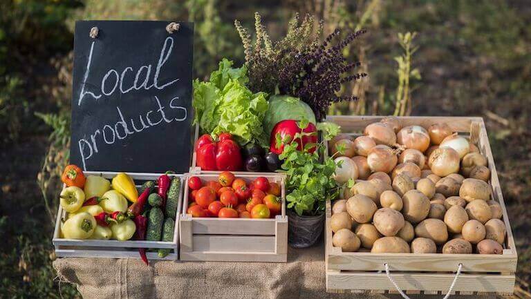 Farm stand with a variety of vegetables and a hand-written sign that reads, "Local products."