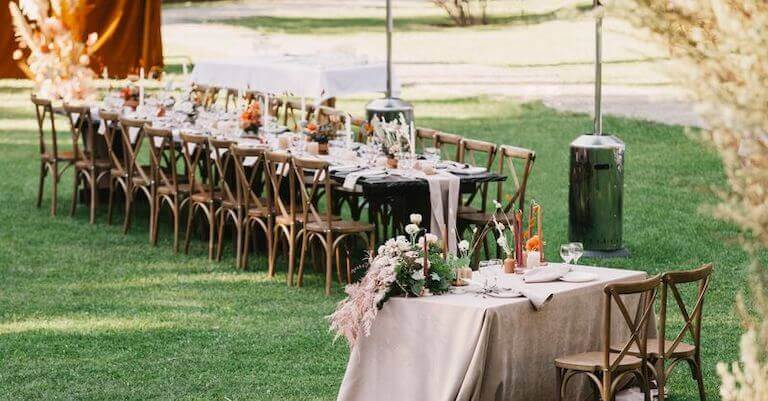 Long table and chairs with light pink decorations set up outside on a lawn