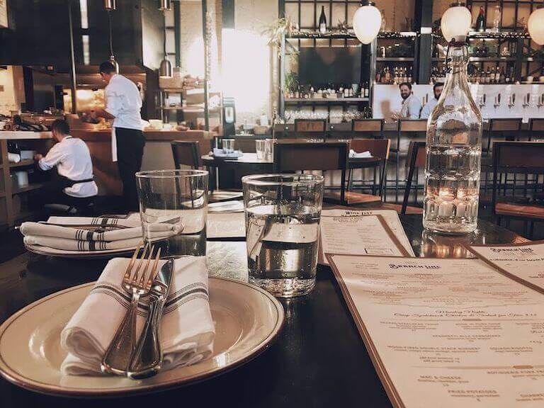 View of a restaurant bar from a table with plates and glasses of water