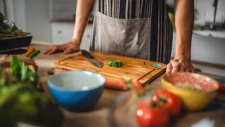 Close up of chopped green onions and a chef standing at the counter