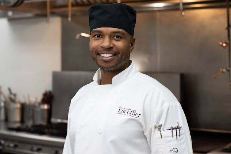 Culinary student in uniform smiling for a photo in a kitchen