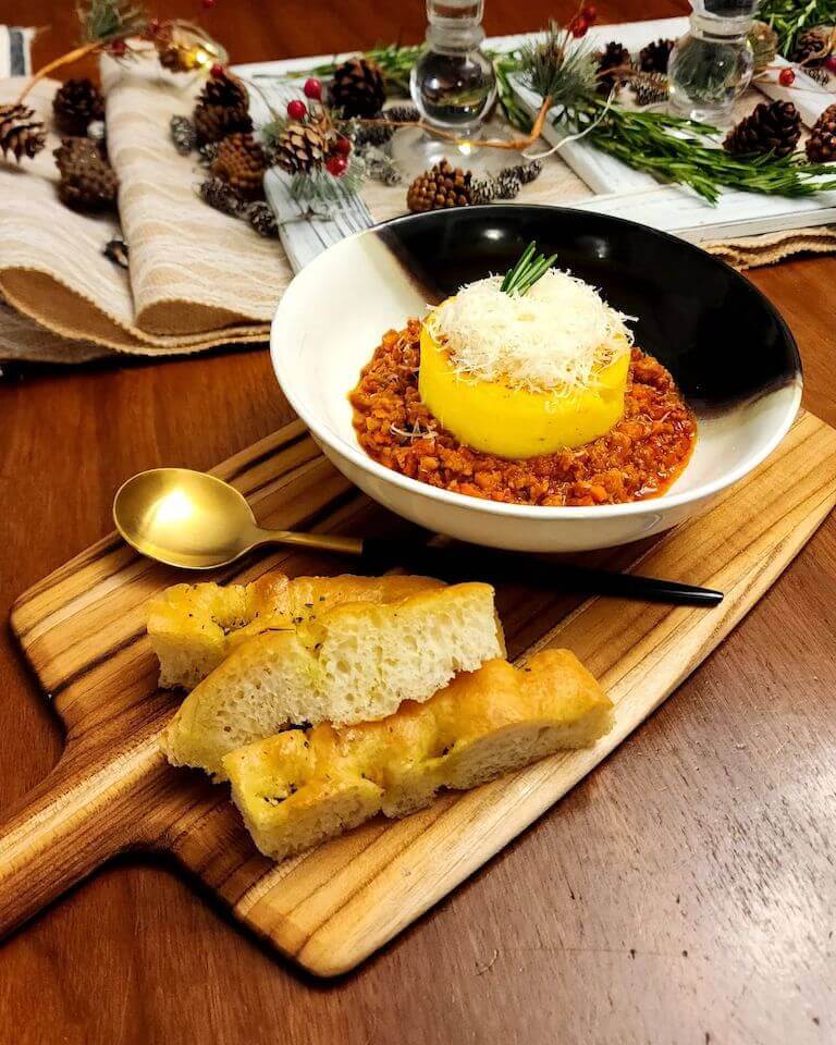 Polenta and Ragu alla Bolognese, and fresh focaccia on a wooden board