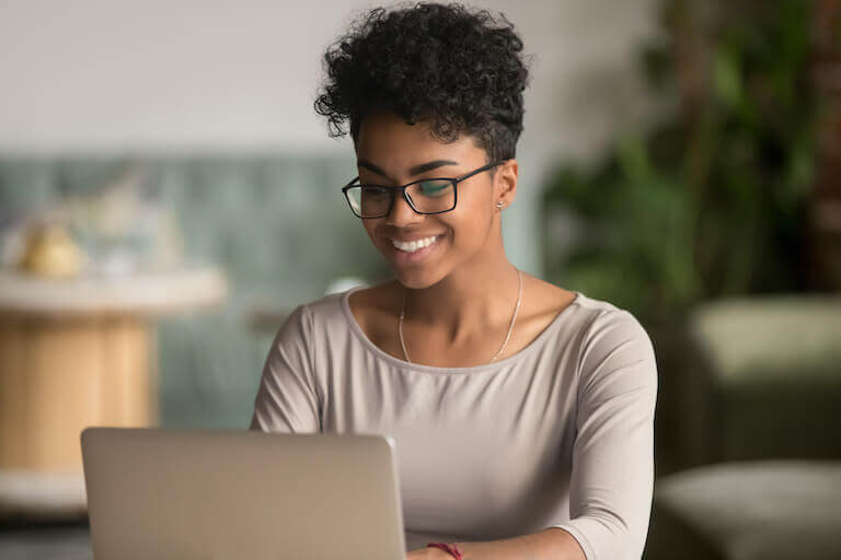 Smiling woman wearing glasses using a laptop in an office space