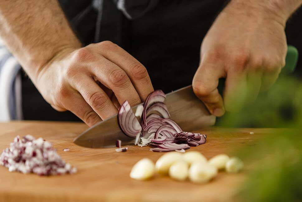 A man cutting onions with a chefs knife
